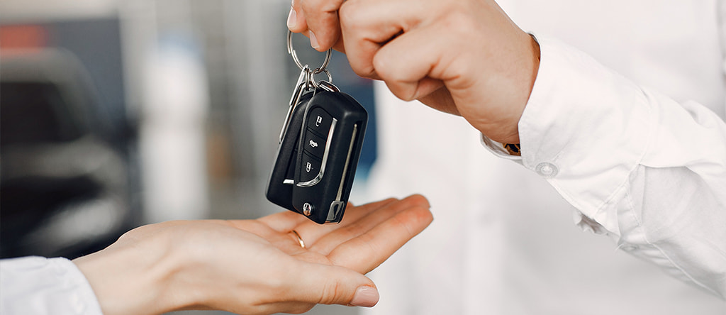 Man's hand giving the car key to woman's hand

