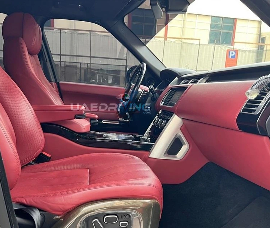 Luxurious red colored interior of a Range Rover Vogue car showcasing its lavish leather seating and elegant steering wheel