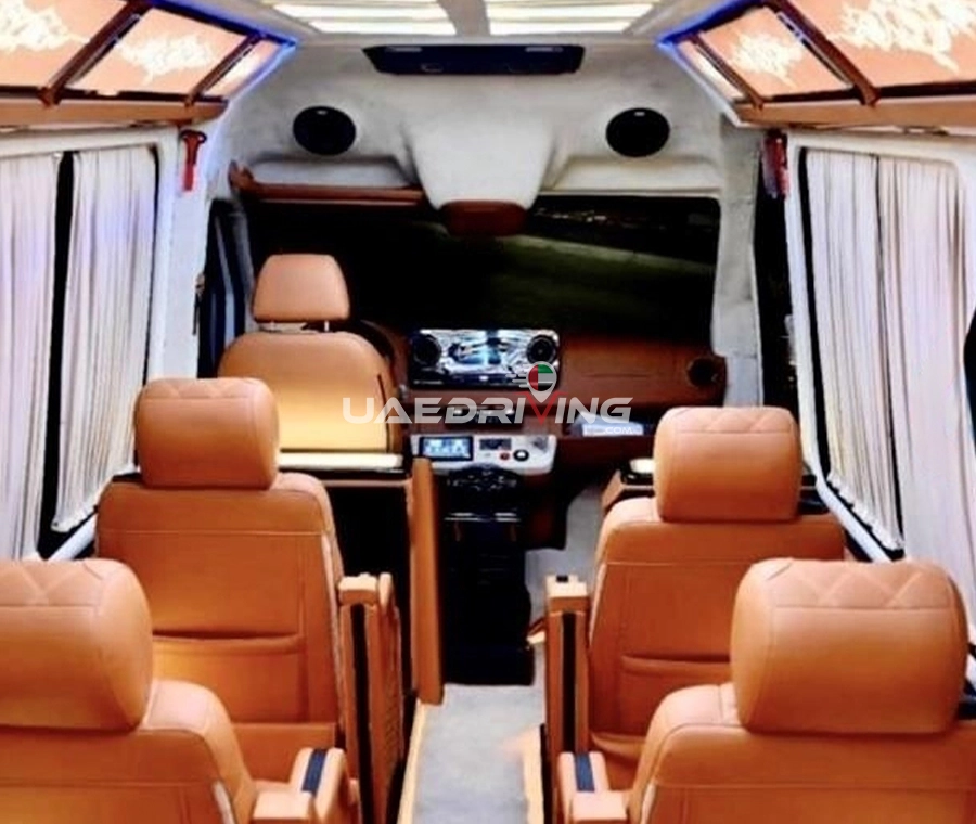 Interior of Mercedes Sprinter 12 Seater showcasing luxurious leather seating and an embedded television screen.