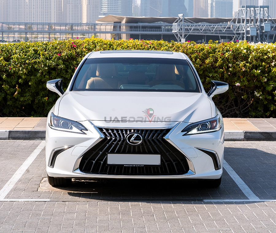 Front view of white Lexus ES350 car, parked in a lot, showcases its elegant design and distinctive features.