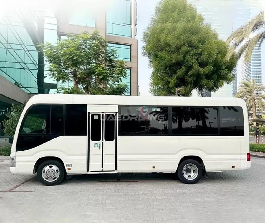 Side view of a white Toyota Coaster 22 Seater bus displaying its distinct features and professional appearance